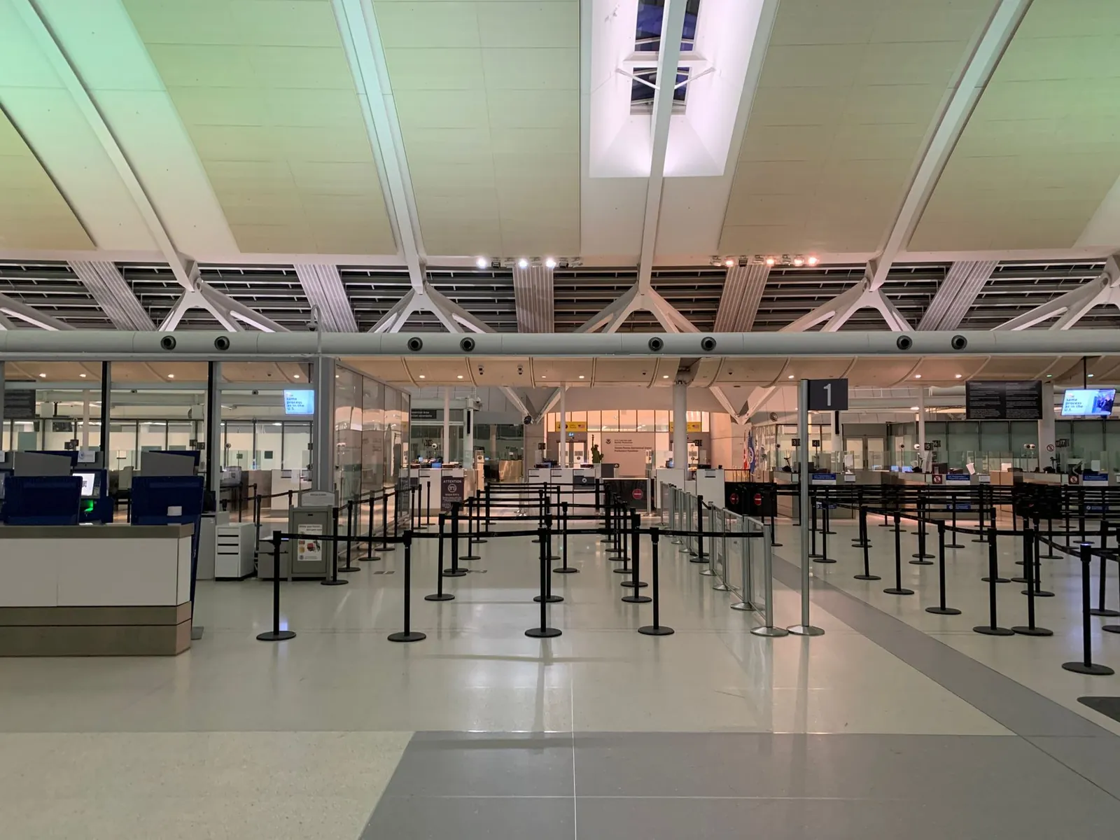 Digital display board showing live security wait times in minutes at a busy airport checkpoint