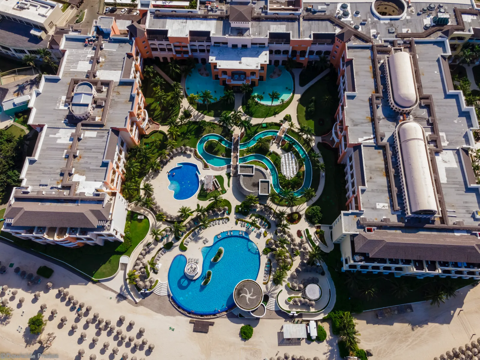 Overhead view of an all-inclusive resort showing pool, beach bars, and dining terraces