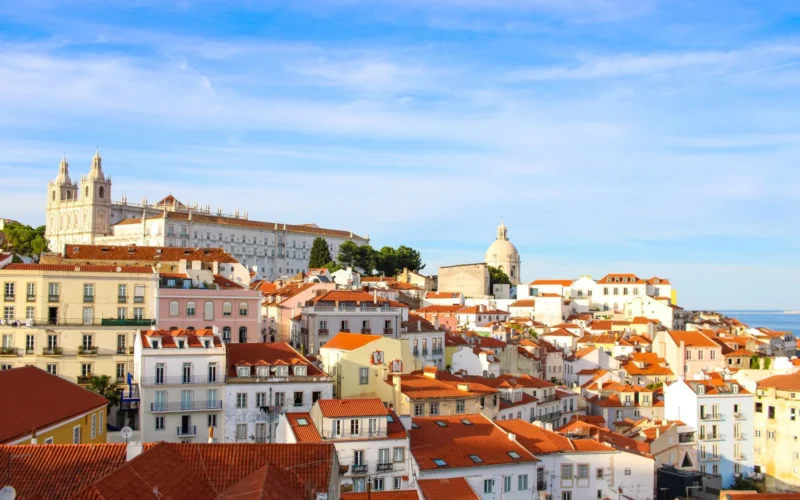 Lisbon waterfront on a clear May morning, with trams and outdoor café tables along the Tagus River