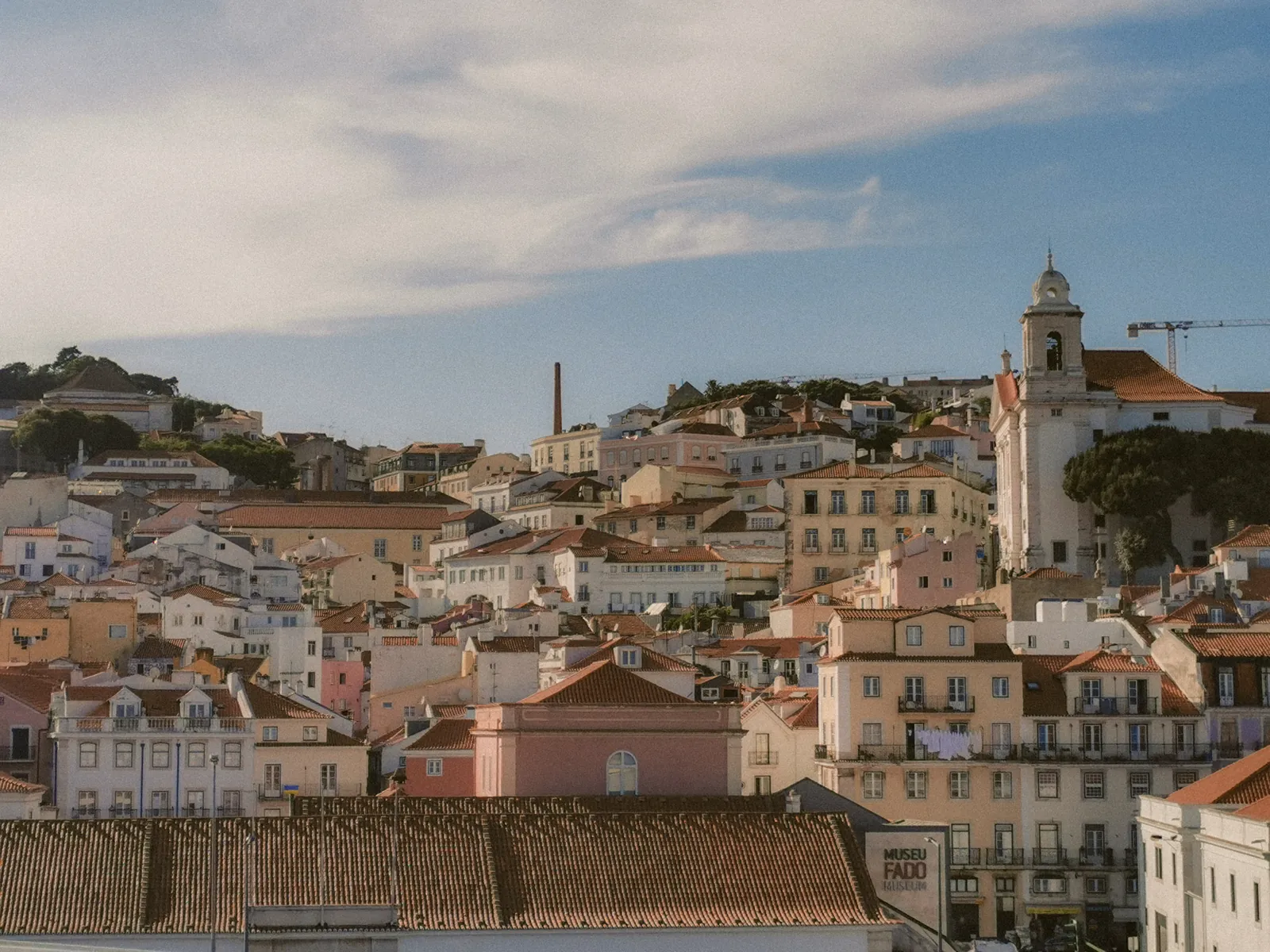 Alfama neighborhood in winter light, wet cobblestone streets and tiled facades with no tourist crowds