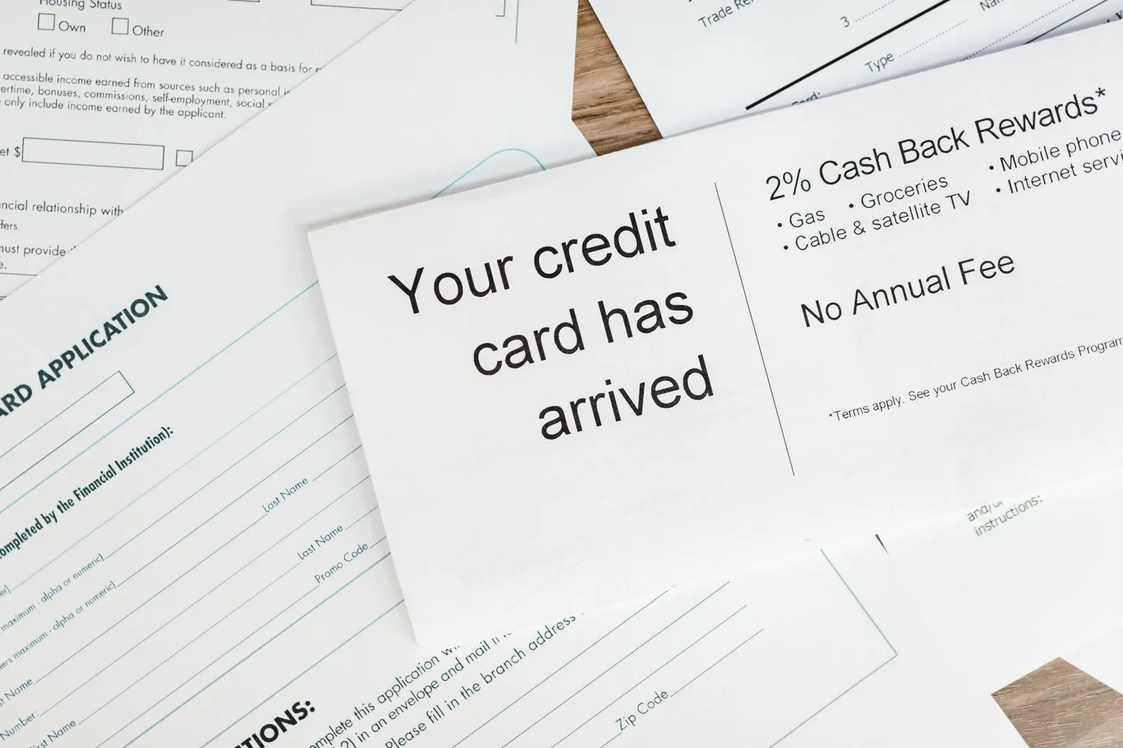 Four travel credit cards fanned out next to a passport and boarding pass on a wooden desk
