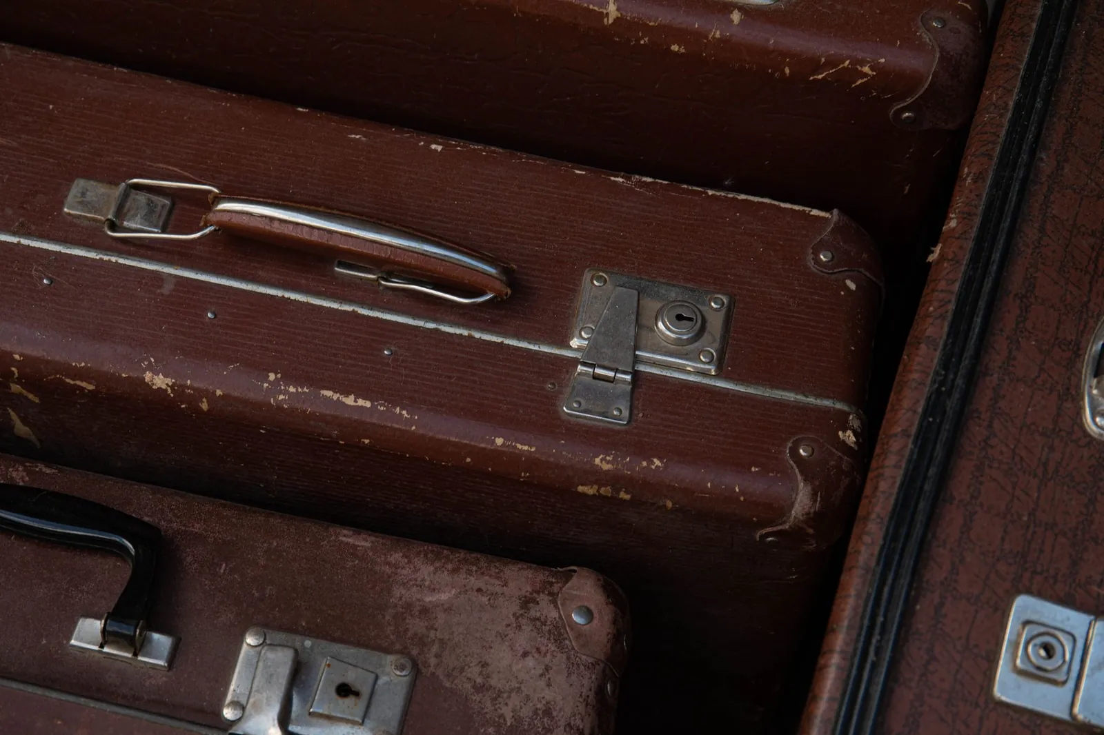 Hard-shell carry-on spinner, soft-shell carry-on, and hybrid travel backpack side by side—three budget luggage options under $100