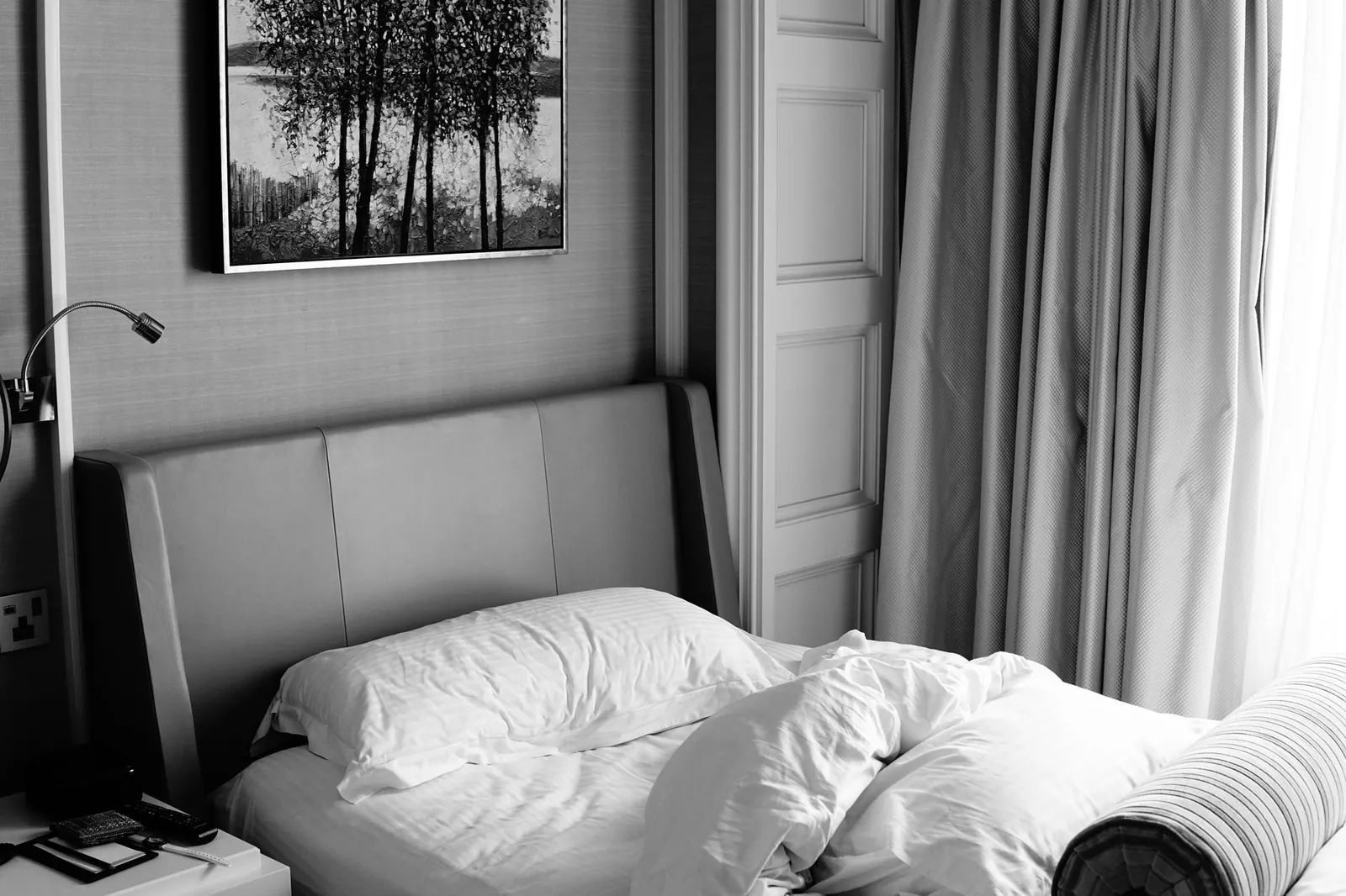 Interior of a Premier Inn hotel room showing a double bed, small desk, and compact bathroom entrance in neutral tones