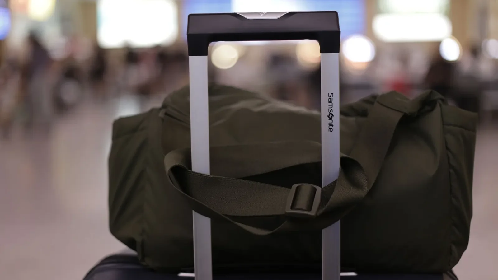 Metal carry-on sizer frame at an airport gate showing 22 × 14 × 9 inch dimensions with a hard-sided roller bag inserted