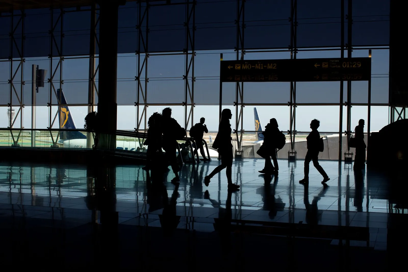 Metal carry-on sizer frame at an airport gate showing 22 × 14 × 9 inch dimensions with a hard-sided roller bag inserted