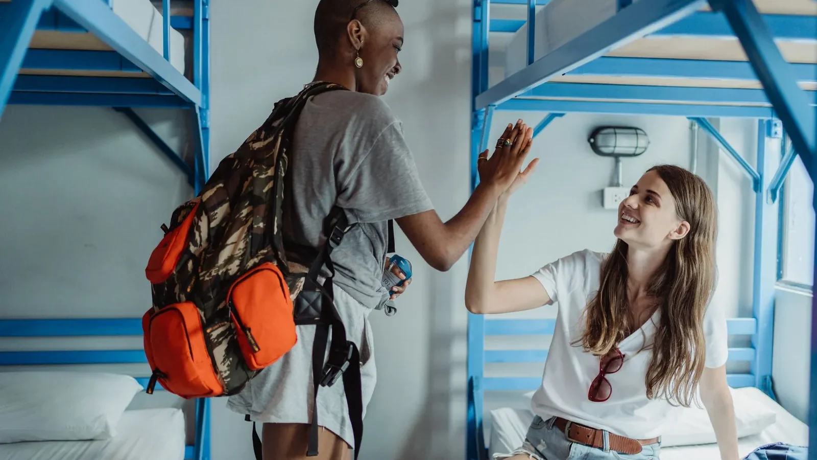 Hostel dorm room with four bunk beds and shared lockers beside a budget hotel room with a double bed and private ensuite bathroom