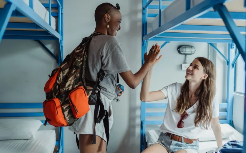 Hostel dorm room with four bunk beds and shared lockers beside a budget hotel room with a double bed and private ensuite bathroom