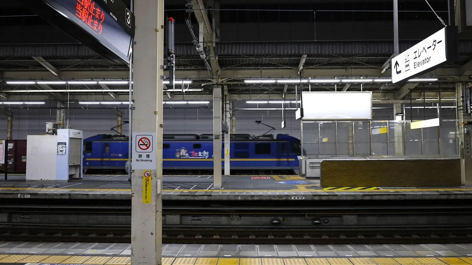 Shinkansen bullet train at a platform in Japan with a departure board overhead