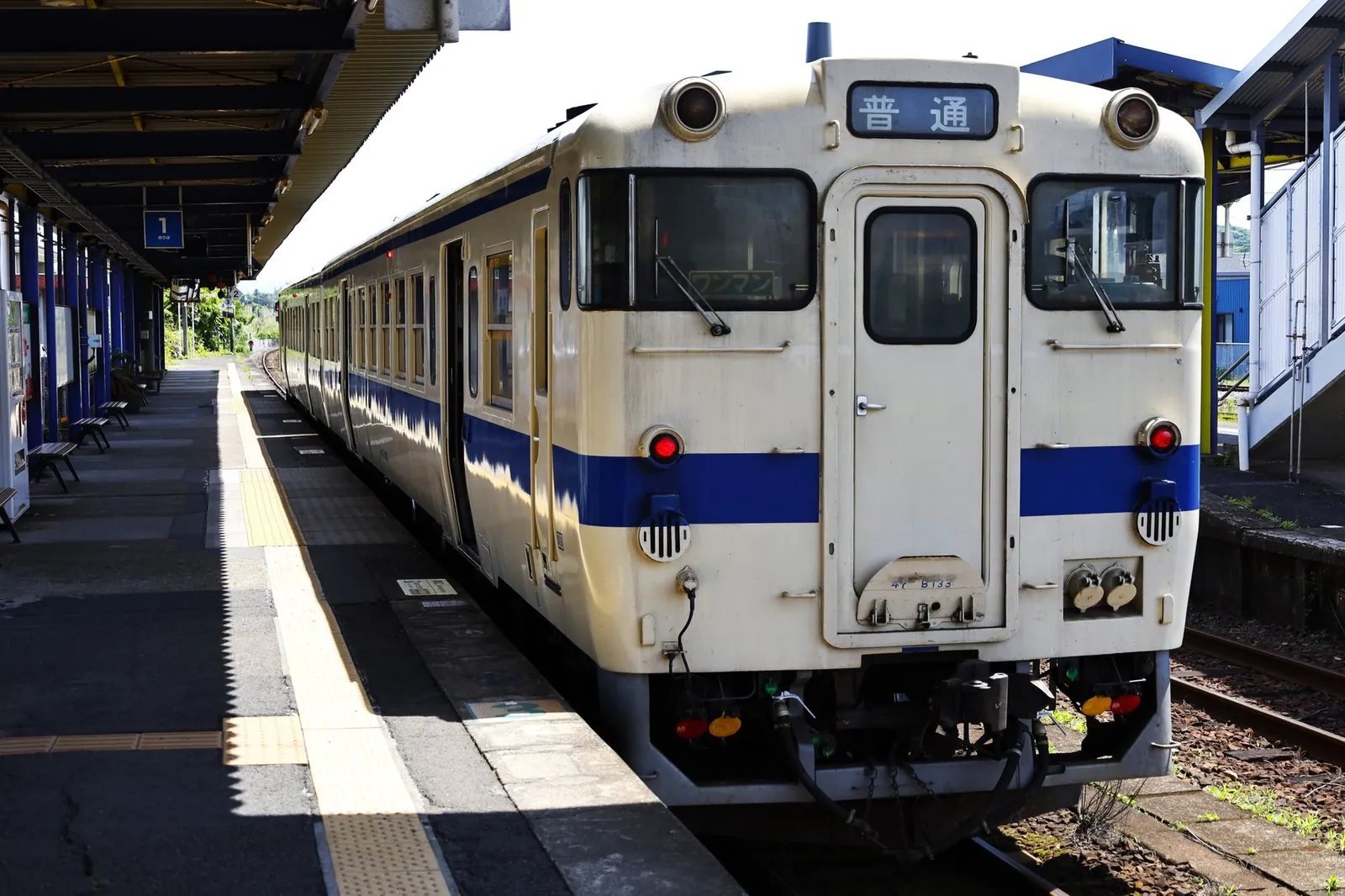 Shinkansen bullet train at a platform in Japan with a departure board overhead