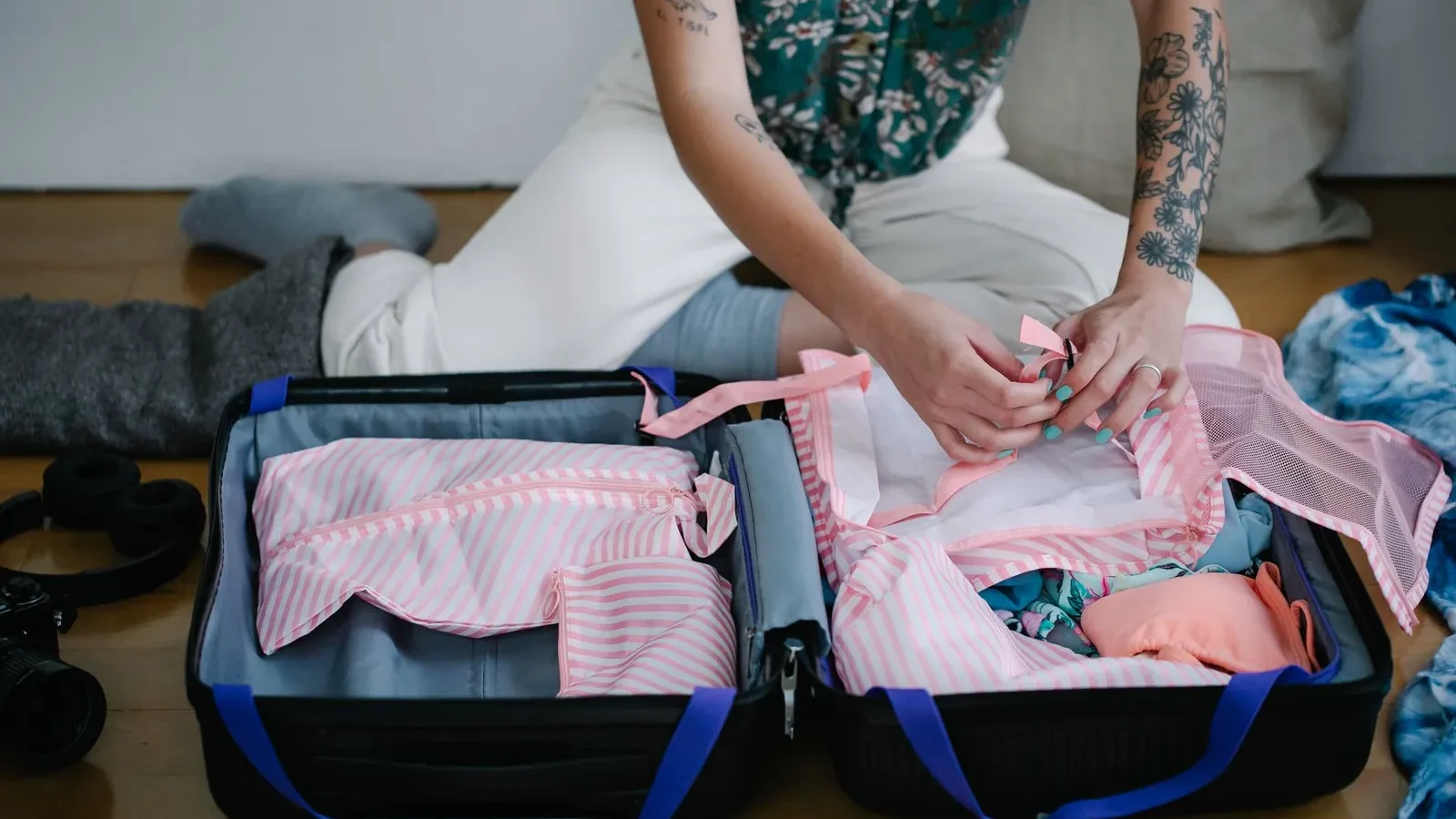 Overhead view of open luggage with rolled clothes organized in packing cubes by category