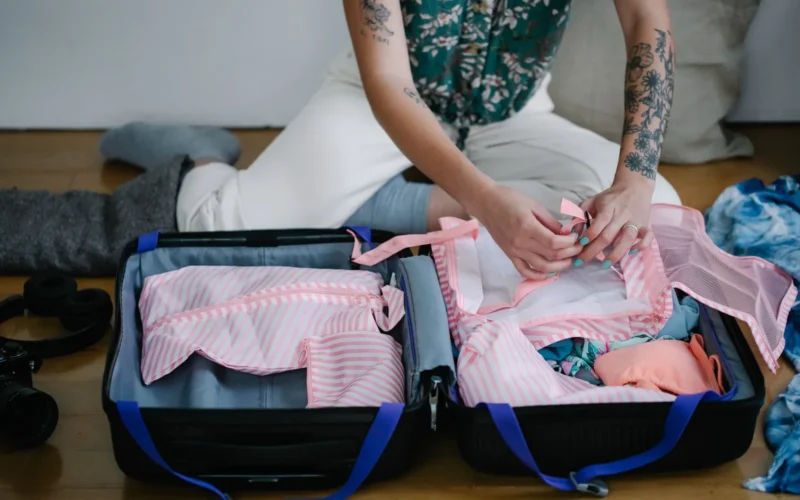Overhead view of open luggage with rolled clothes organized in packing cubes by category
