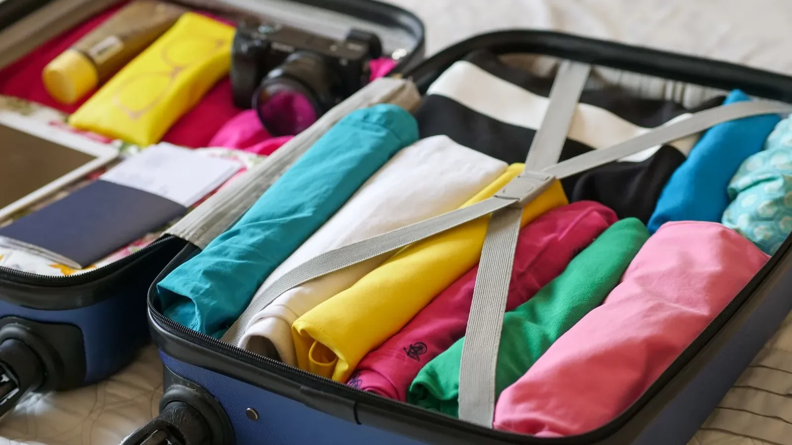 Flat lay of folded merino tops, dark trousers, a waterproof jacket, and broken-in walking shoes arranged for a two-week Europe trip