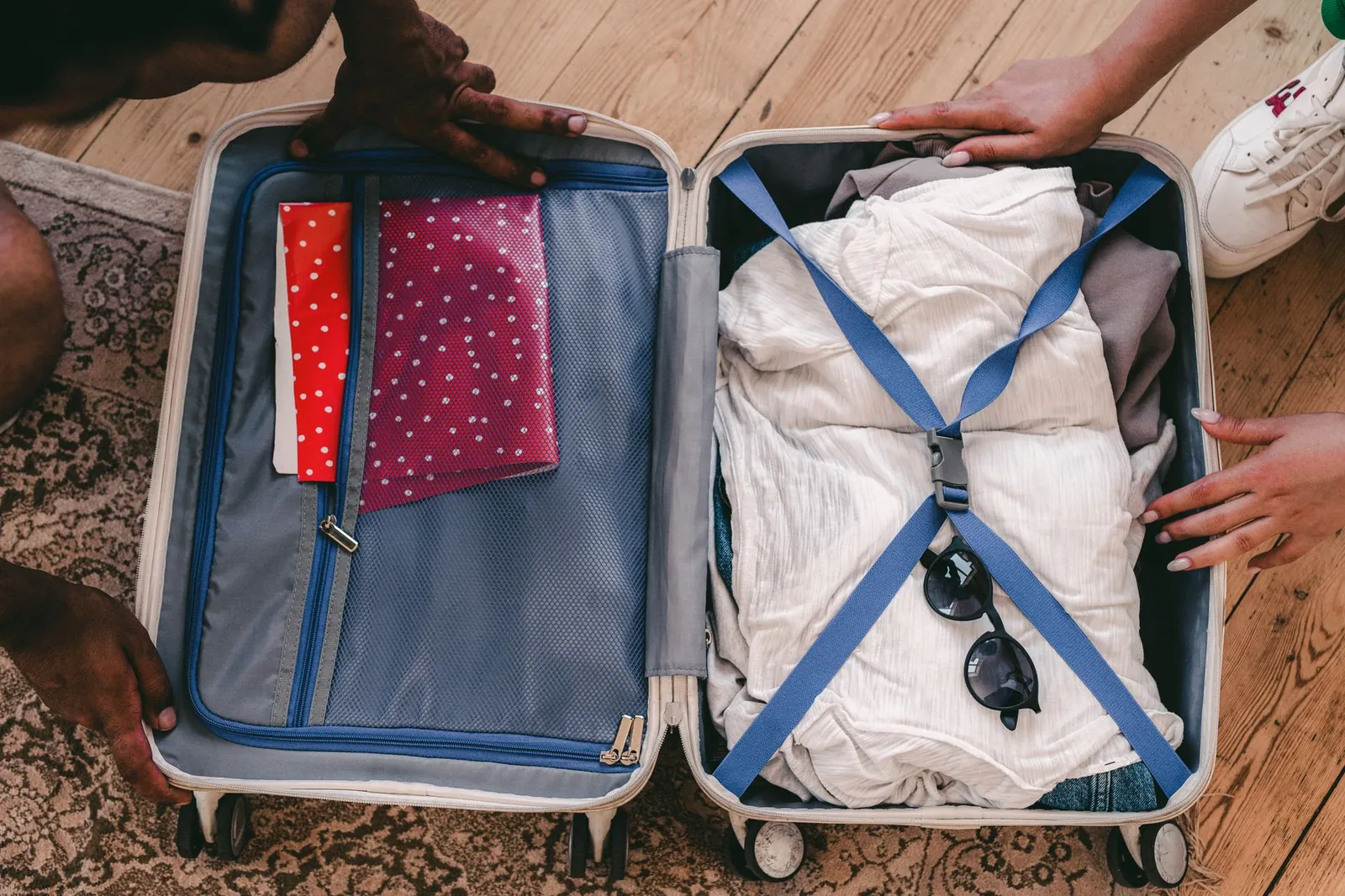 Flat lay of folded merino tops, dark trousers, a waterproof jacket, and broken-in walking shoes arranged for a two-week Europe trip