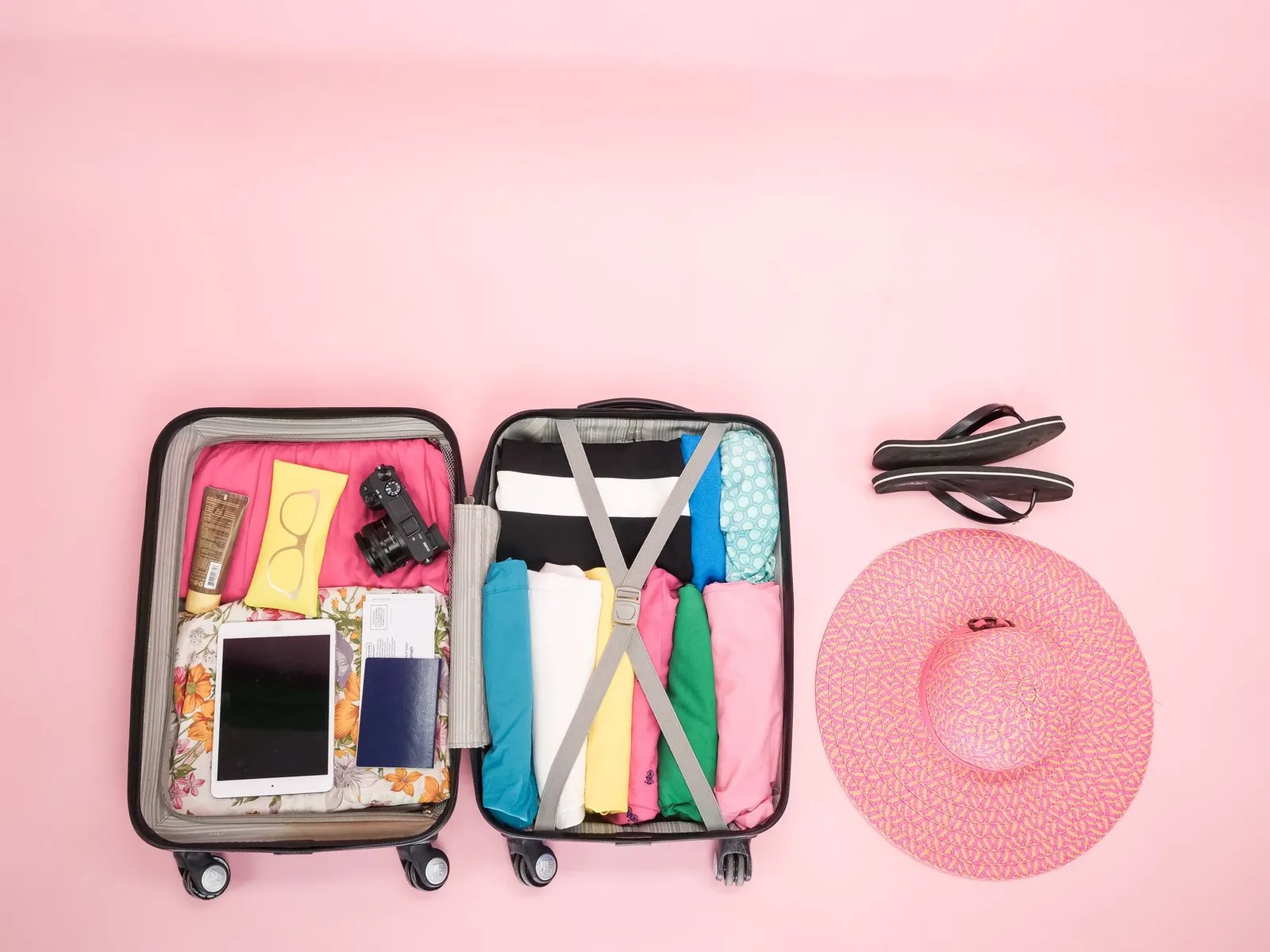 Open carry-on suitcase showing packing cubes with clothes, a small toiletries bag, and a universal adapter with space remaining at the top