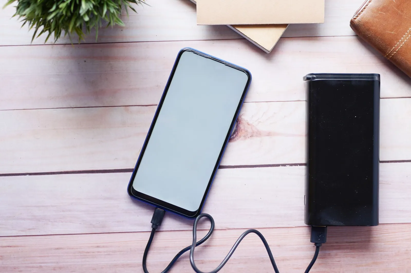 Close-up of portable charger ports showing USB-C and USB-A connections with cables plugged into phone and tablet simultaneously
