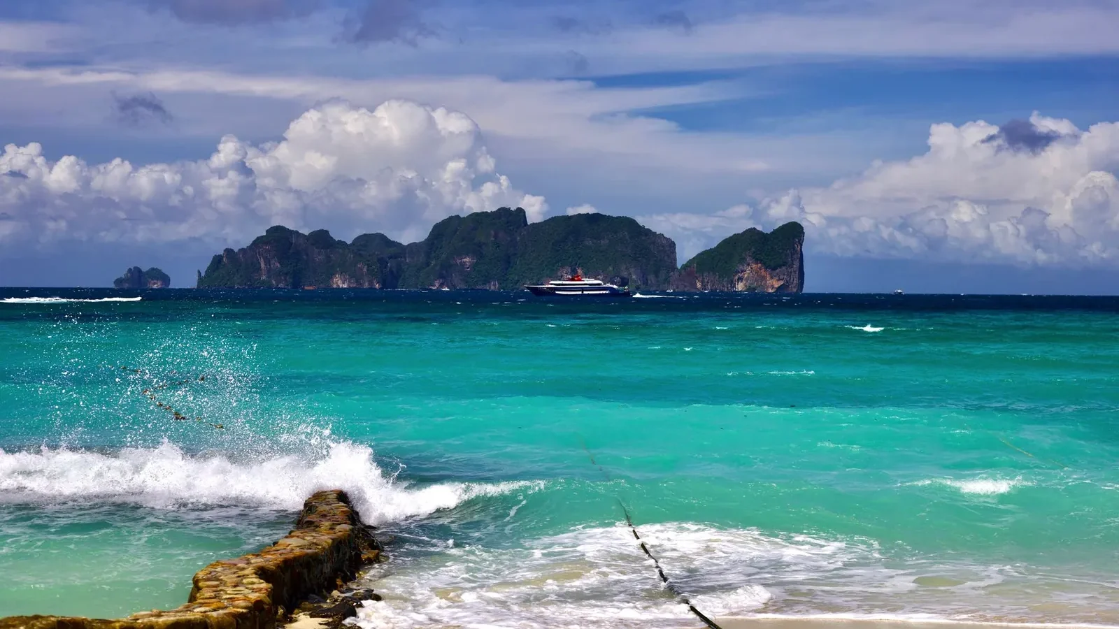 Patong Beach in Phuket with jet skis, beachfront hotels, and crowded sand during daytime