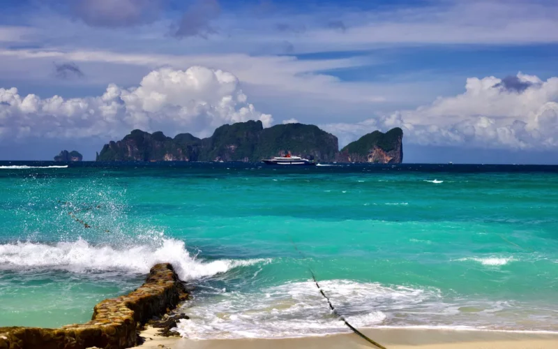 Patong Beach in Phuket with jet skis, beachfront hotels, and crowded sand during daytime