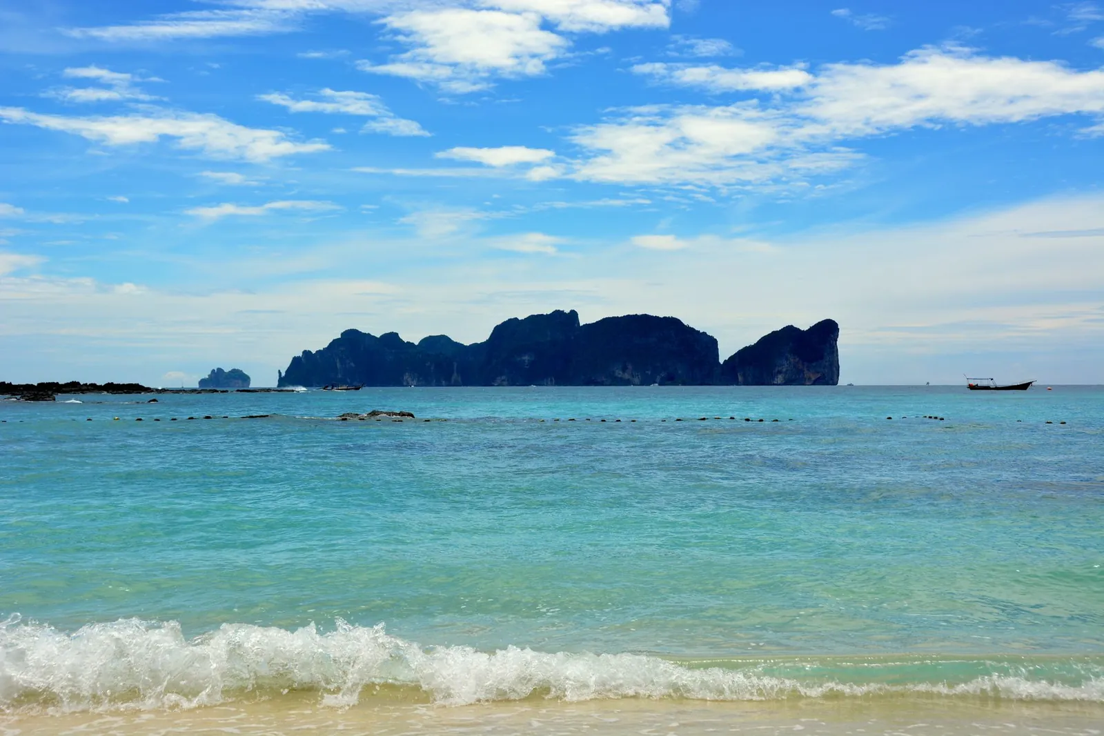 Patong Beach in Phuket with jet skis, beachfront hotels, and crowded sand during daytime