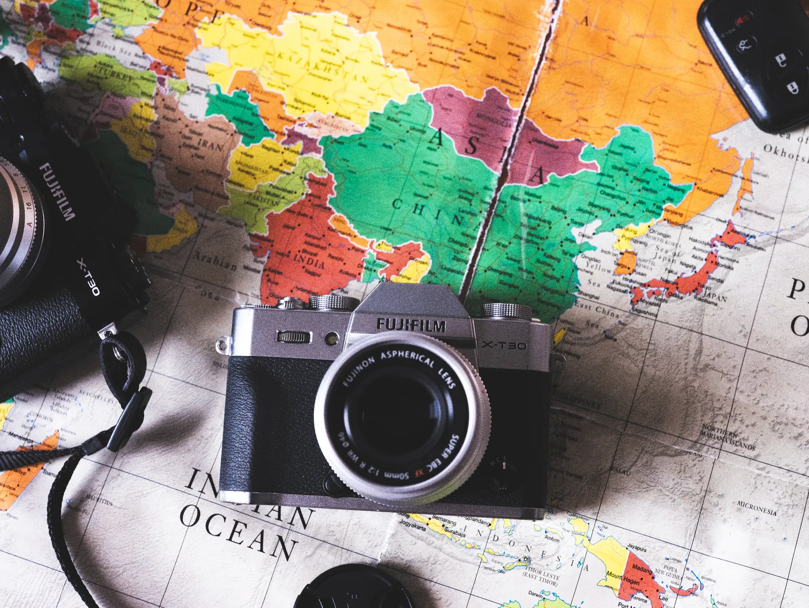 Compact carbon fiber travel tripod next to a mirrorless camera body for size comparison